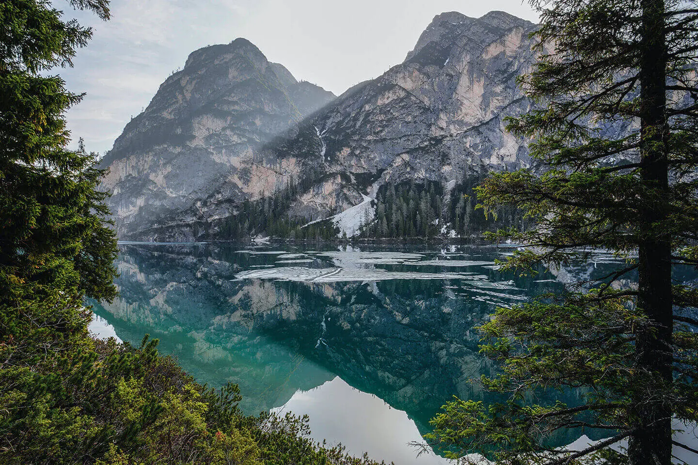 A lake with mountains in the background and trees around it.