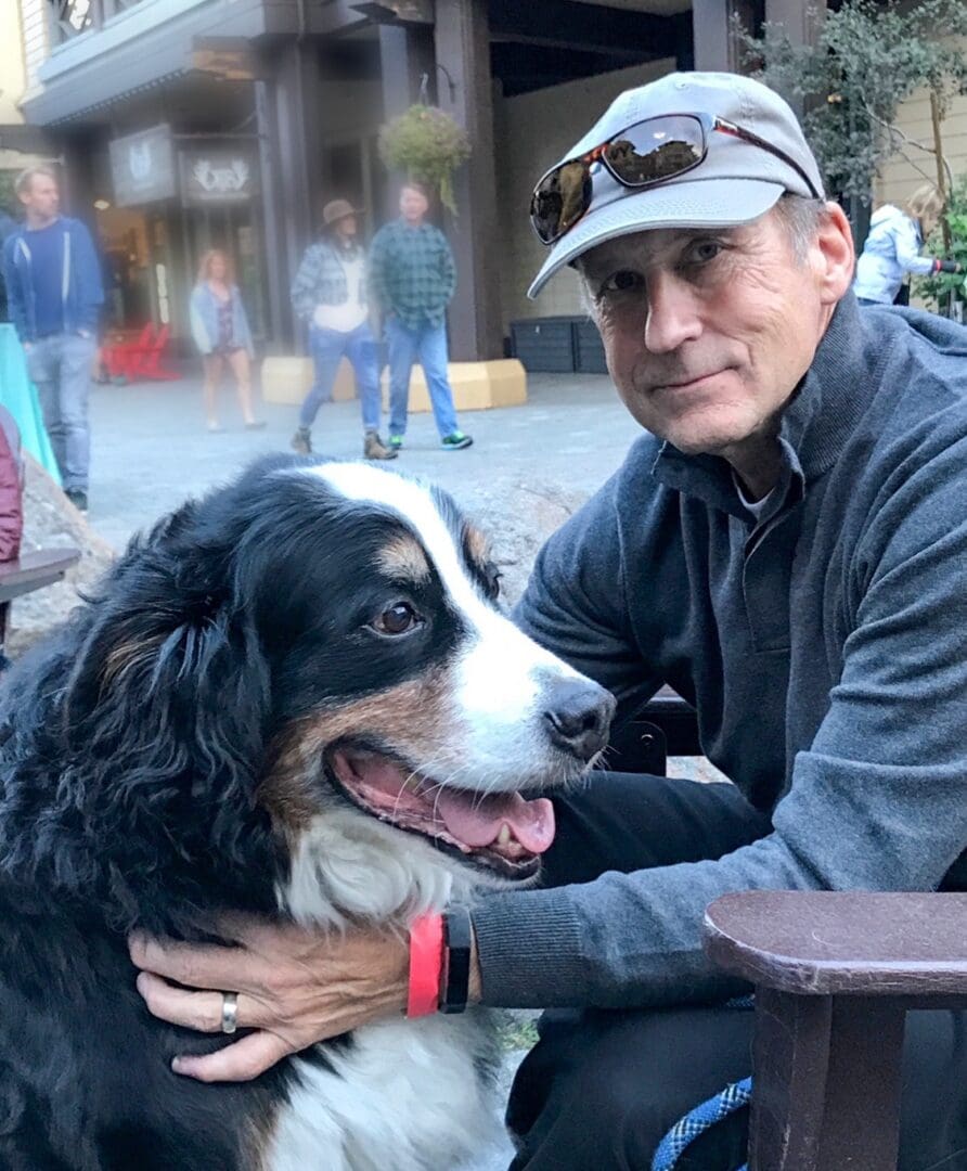 A man sitting on top of a bench with his dog.